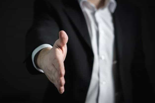 A businessman holds out his hand for a handshake.