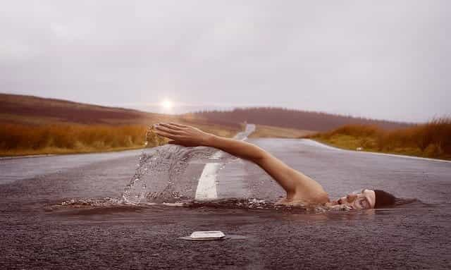 A swimmer swimming through a paved, empty road.