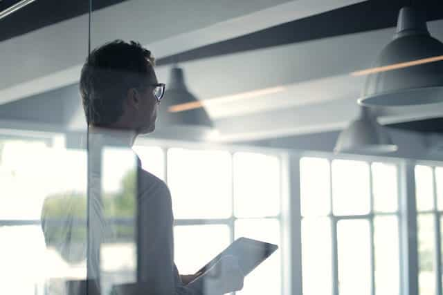 A businessman holding an iPad in an office.