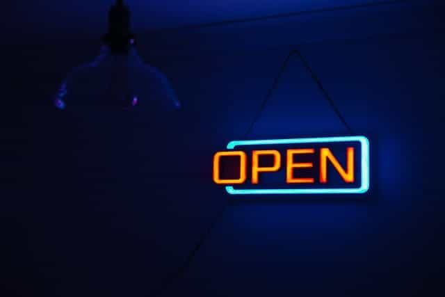 A red and blue neon sign displaying the word Open on the wall of a business.