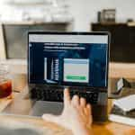 A person sitting in front of a laptop which is displaying an article on how to increase one’s revenue while keeping satisfaction consistent.