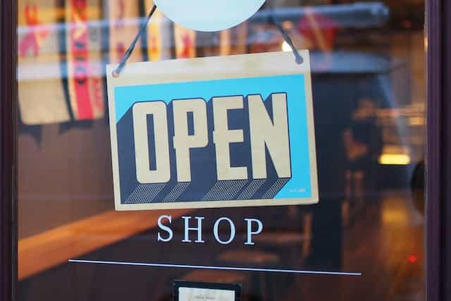 A white and blue OPEN sign on a shop window.